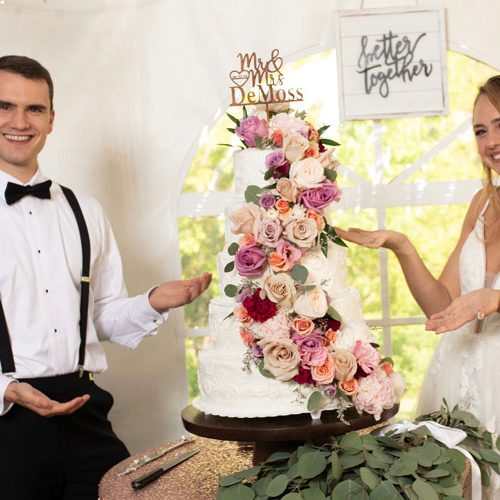 bride and groom about to cut wedding cake with flowers