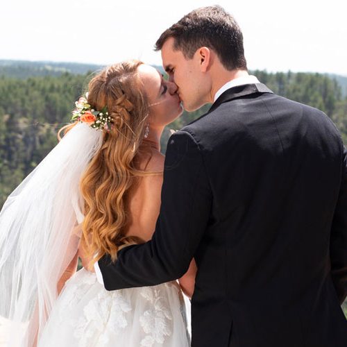bride and groom kissing with wedding flowers in veil