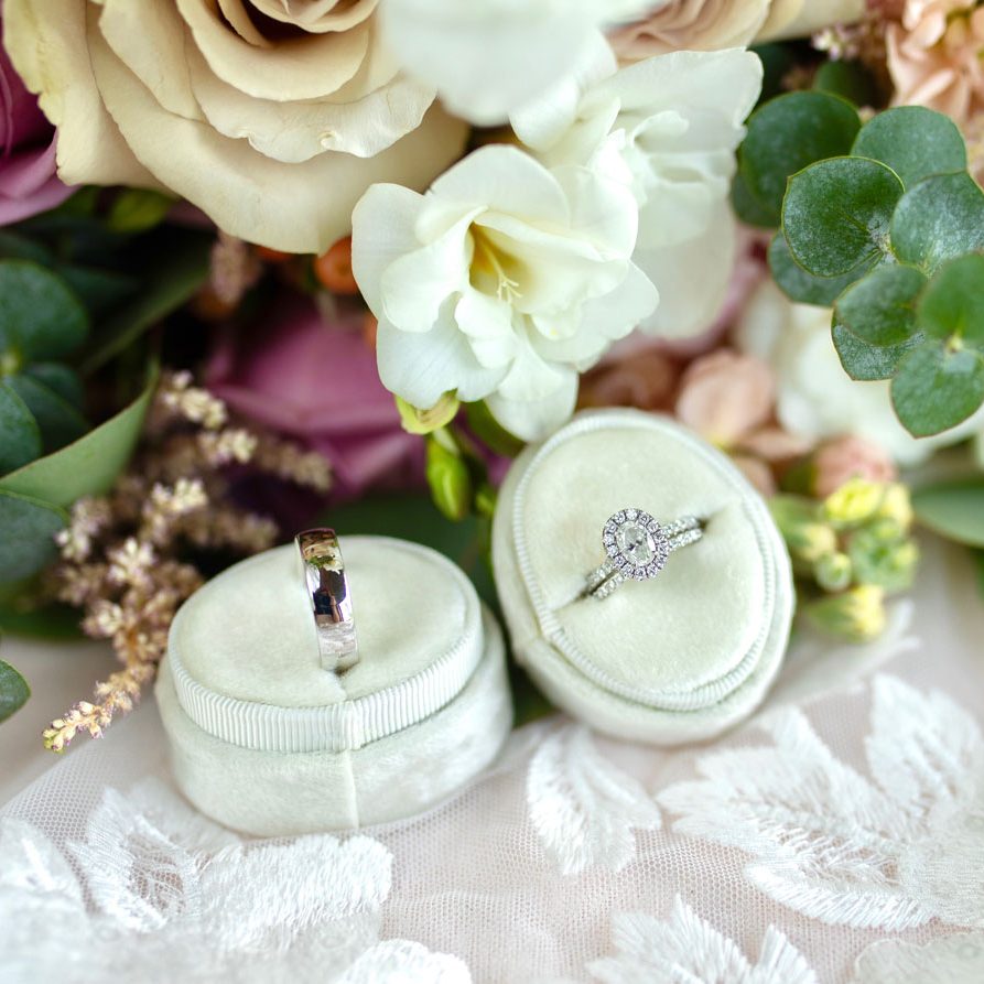 wedding flowers surrounding bride and groom rings