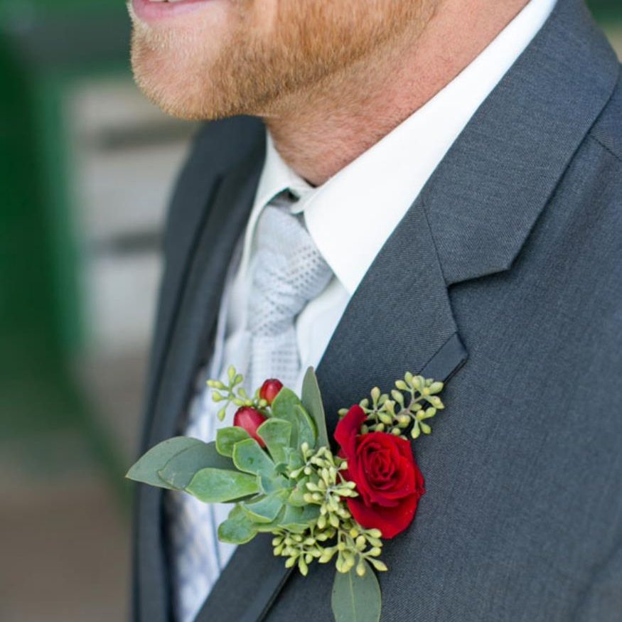Red rose boutonnière attached to a grooms suit