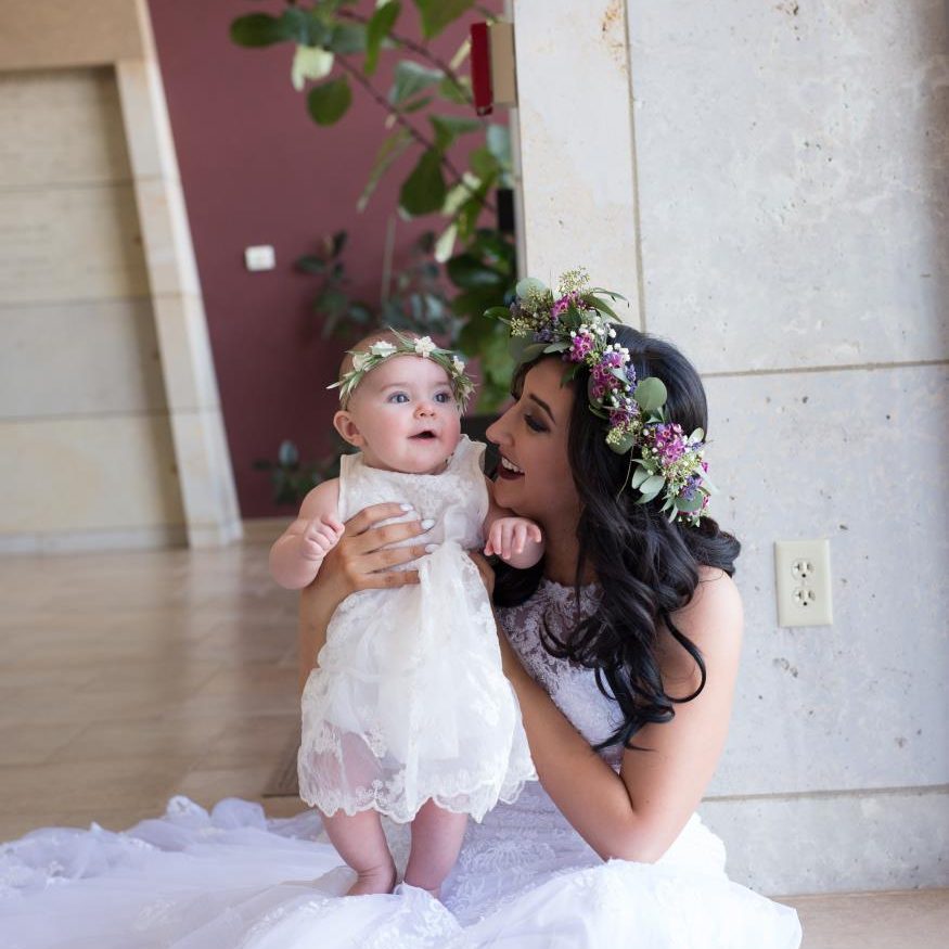 Bride holding her daughter while both are wearing flower crowns